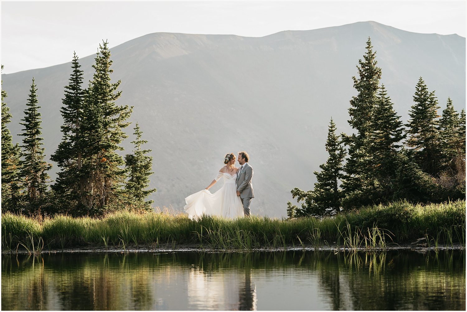 Bride and groom reflection on alpine lake in Crested Butte