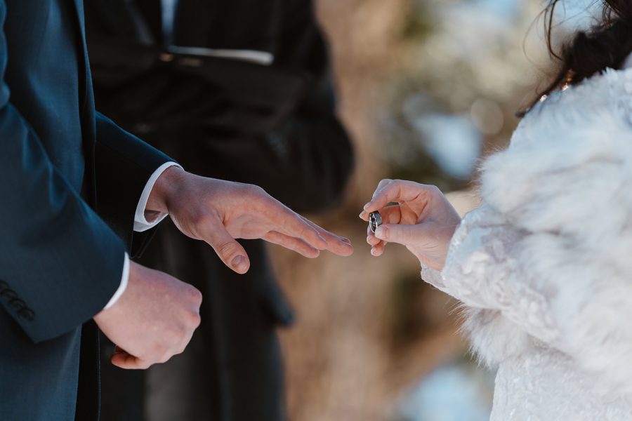 A bride places the ring on her new husbands finger during their Breckenridge winter elopement ceremony in Sapphire Point Overlook. 