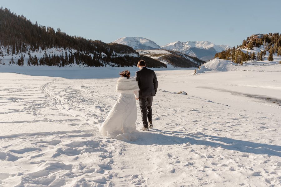 A bride and a groom walk off together during their Breckenridge winter elopement among the mountain peaks and the brisk mountain air. 