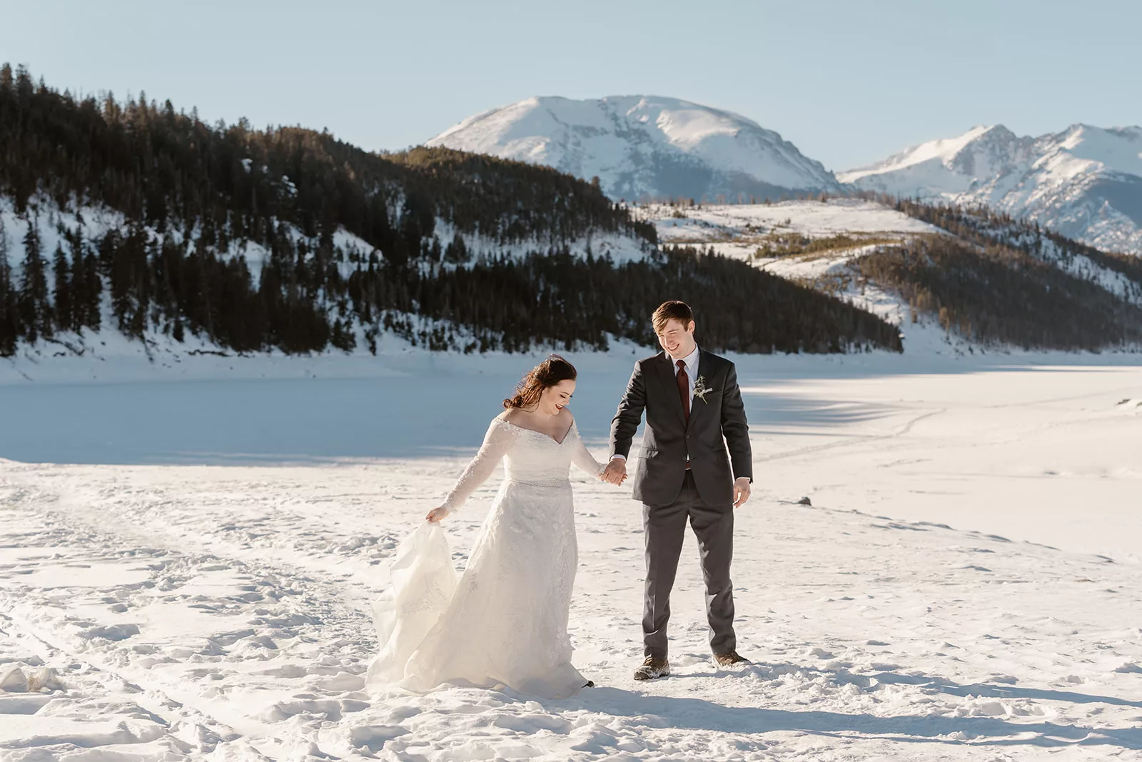 A couple walks along the snowy landscape during their winter breckenridge elopement.