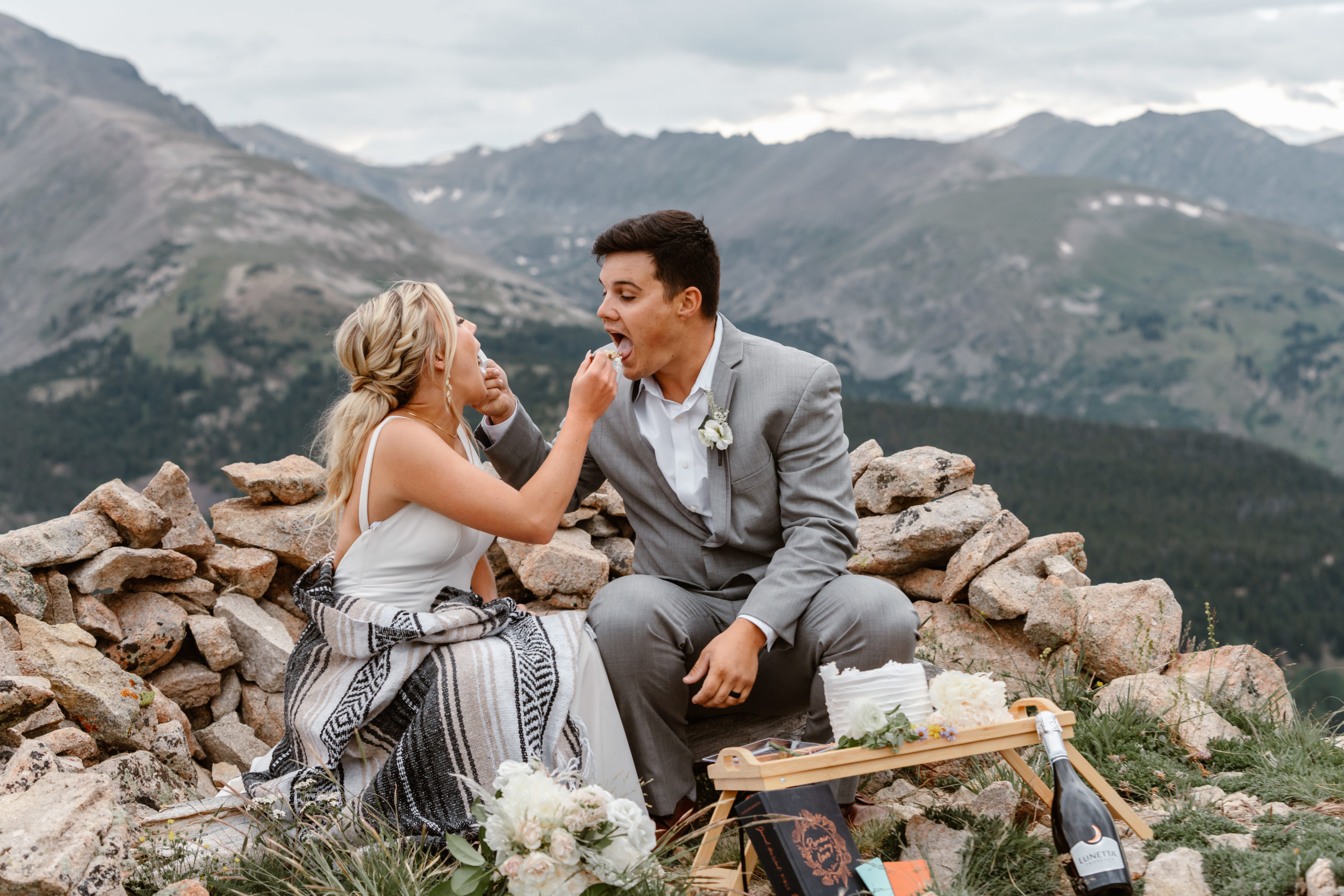 A bride and groom share their wedding cake on top of a Sapphire Point elopement.