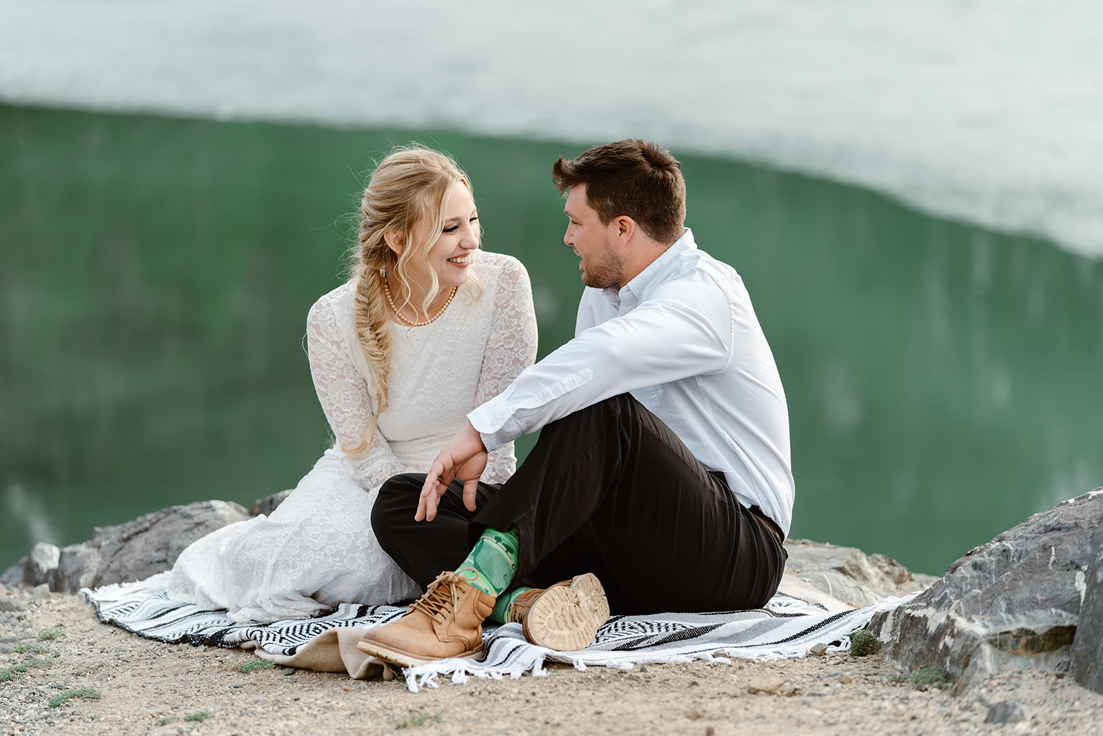 An eloping couple sit by a lake as they experience their Spring elopement in Breckenridge.