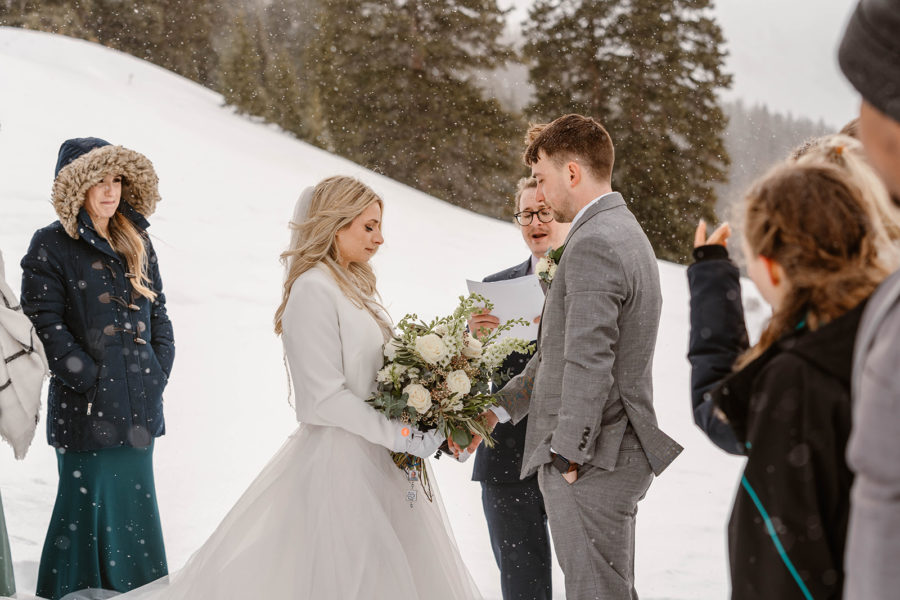 A bride and groom say their vows during their snowy elopement ceremony in Breckenrige.