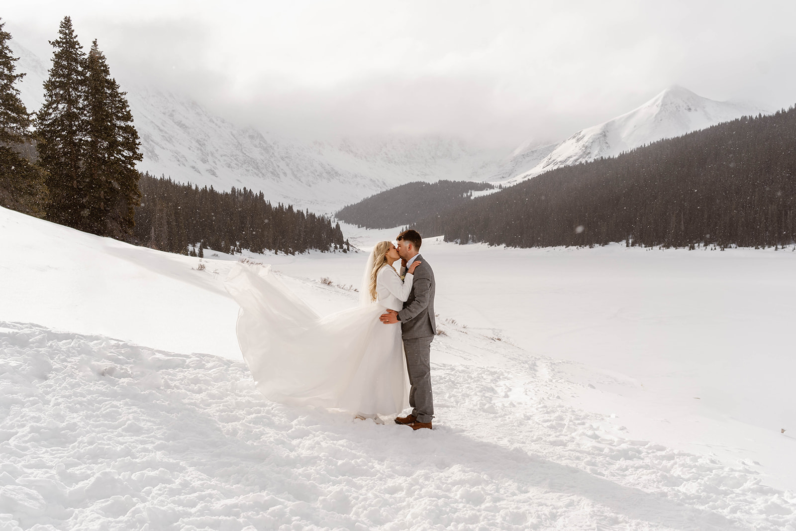 A bride and groom hold each other close among the white, snowy blanket of a Breckenridge Spring day at their Breckenridge Ski Resort wedding.