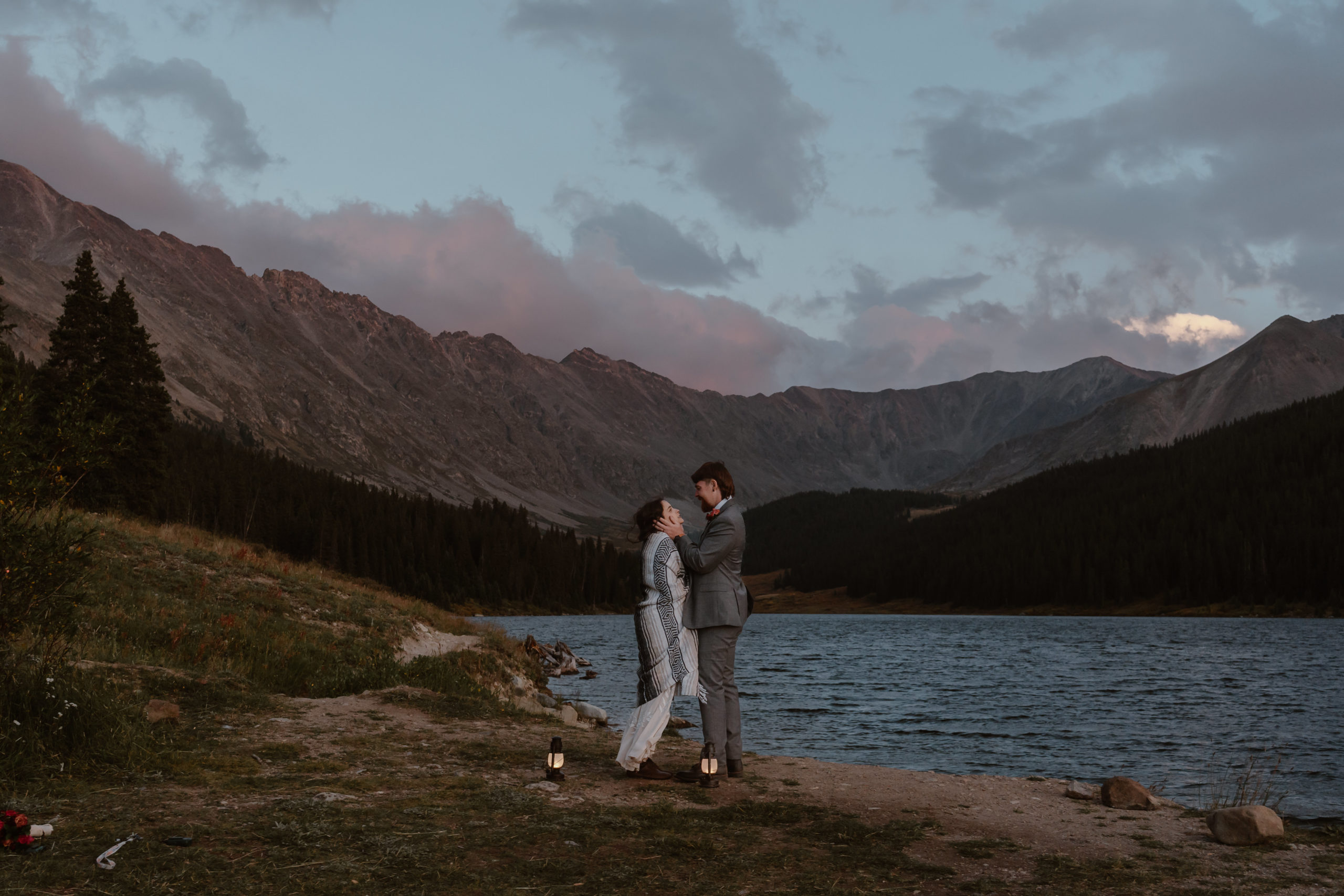 A bride and groom lean in for a kiss next to an alpine lake during their Breckenridge mountain elopement.