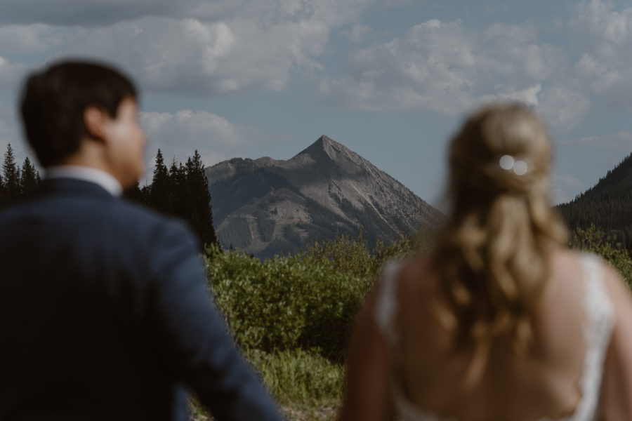 A husband and wife look out at a mountain peak during their summer Crested Butte elopement.