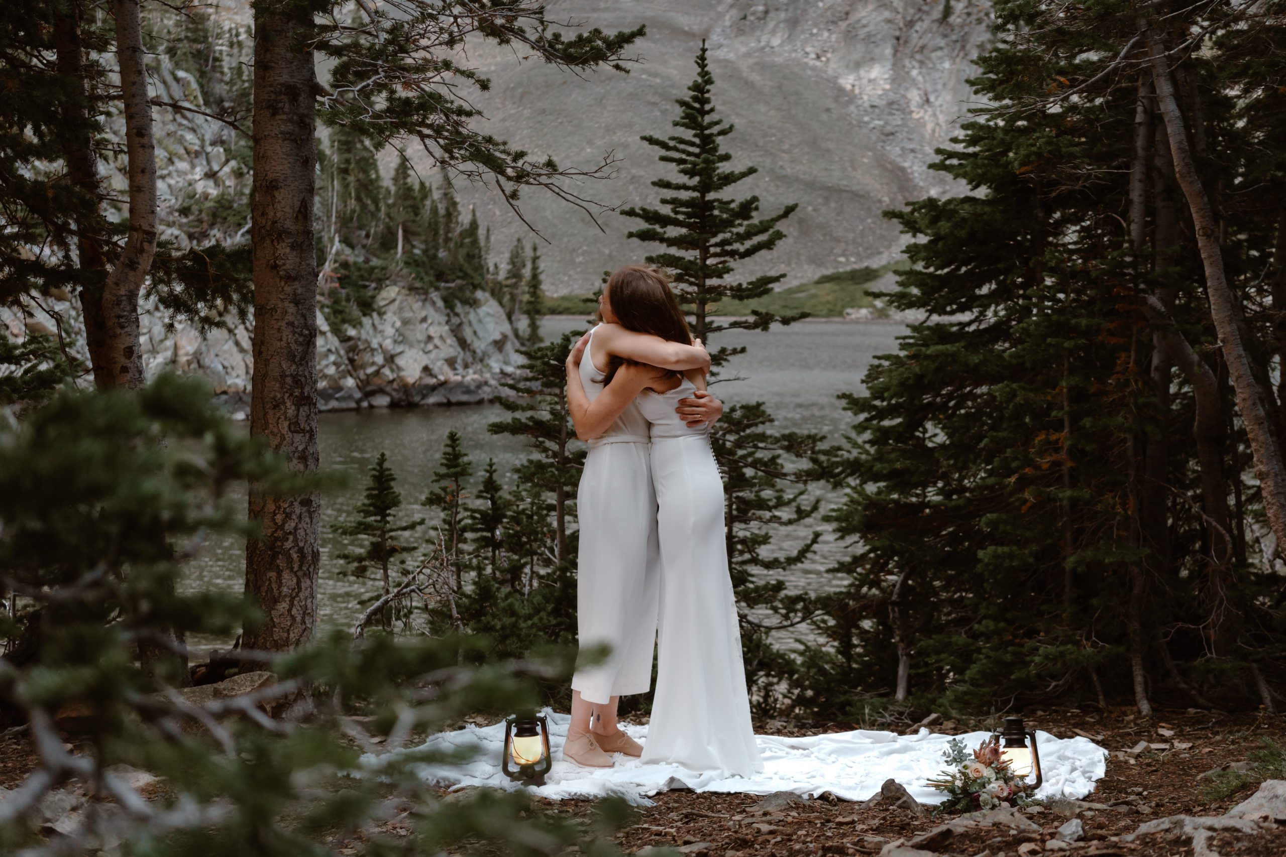 Two brides hug each other close after their first look at their sunrise mountain elopement.