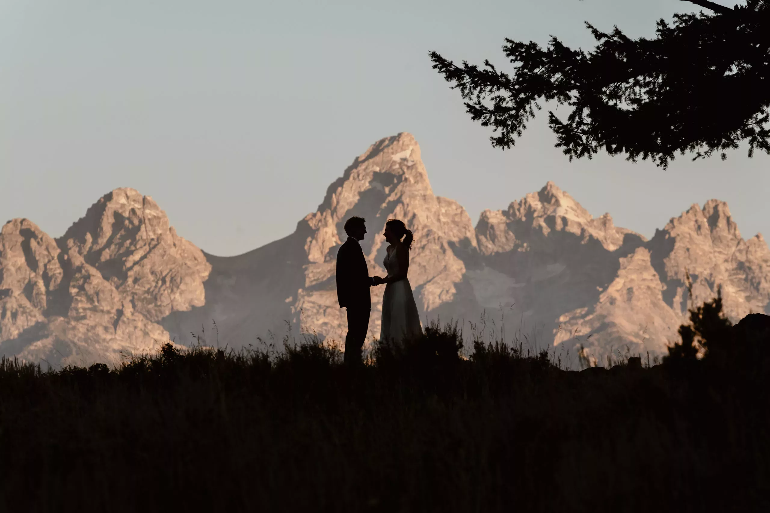A bride and groom share their intimate vows in front of the alpineglow of the Tetons during their Grand Teton National Park elopement.