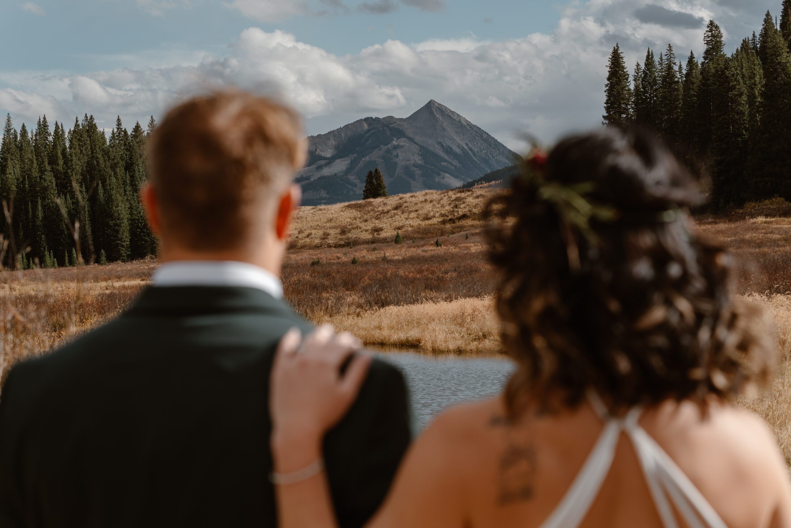 A bride and groom hold eachother close as they look out on the gorgeous Crested Butte mountainscape during their Colorado waterfall elopement.