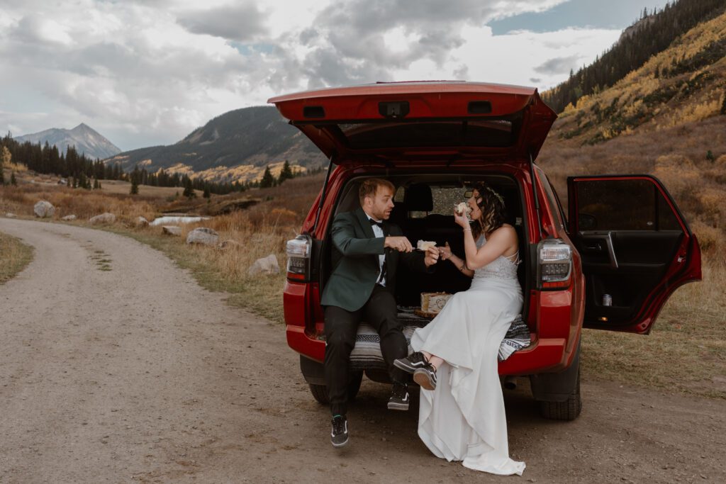 A couple sits in the back of their off-road vehicle, taking a break from their 4x4 wedding.