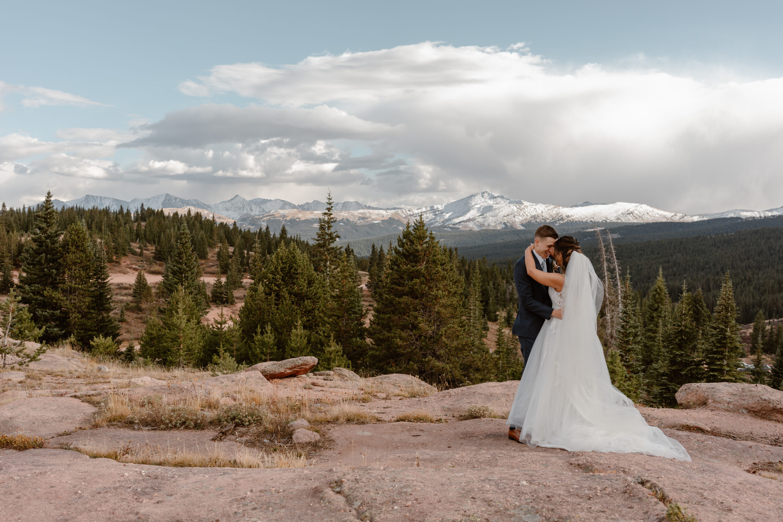 A bride and groom have their first kiss on a mountaintop during their Fall Vail elopement ceremony.