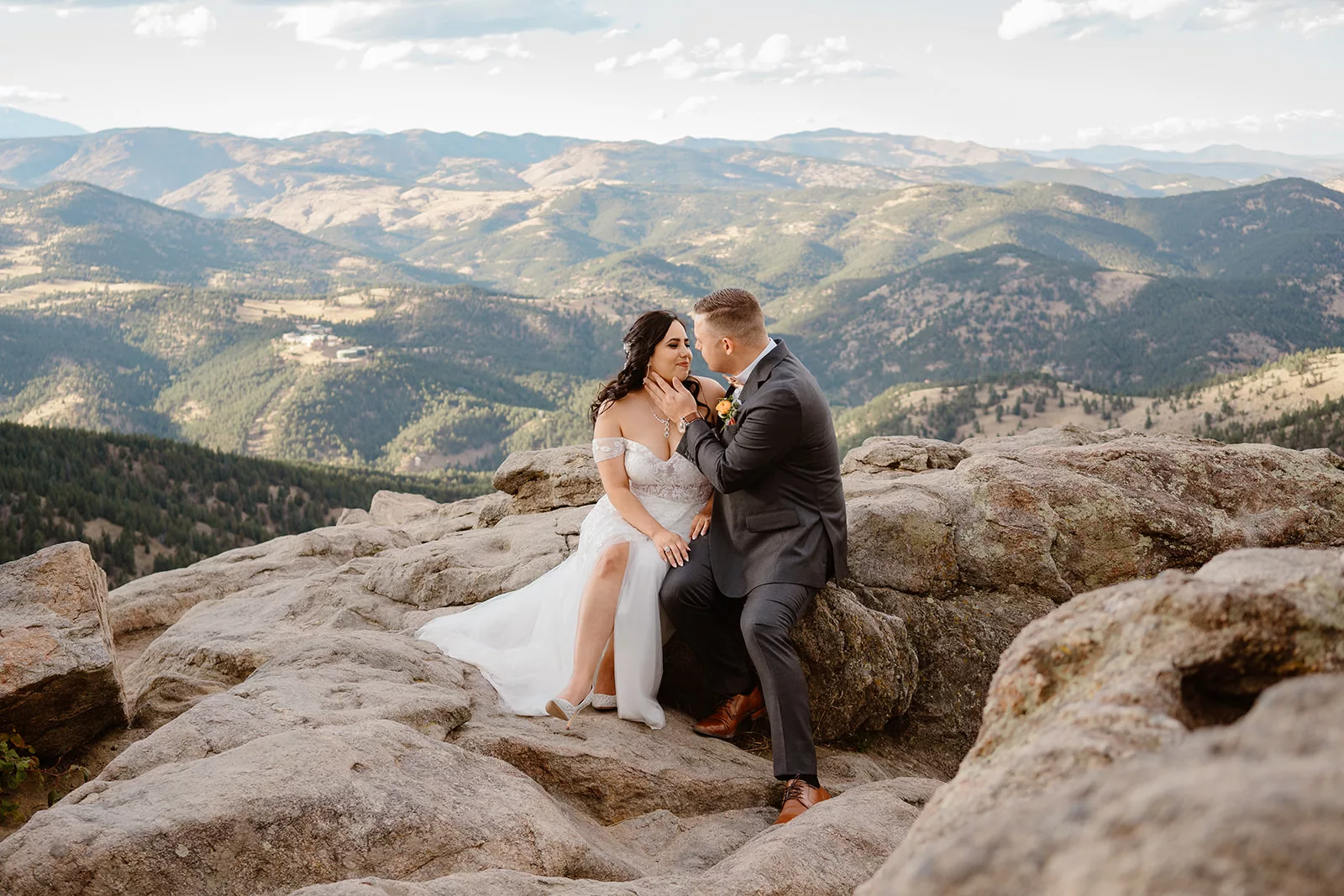 A bride and groom sit among a mountain range during their Colorado adventure elopement.