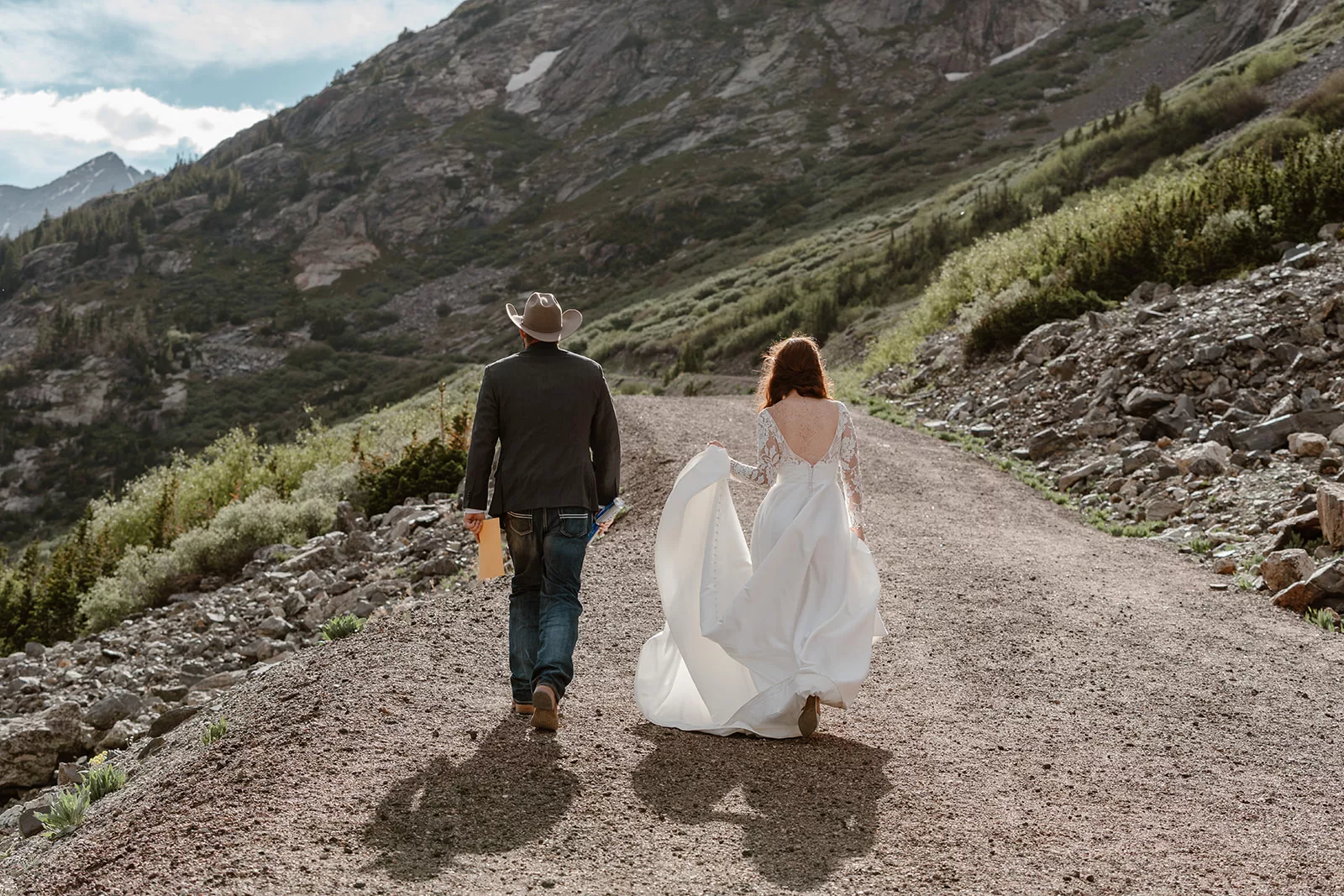 A bride and groom make their way down a trail during their adventure elopement in Colorado.
