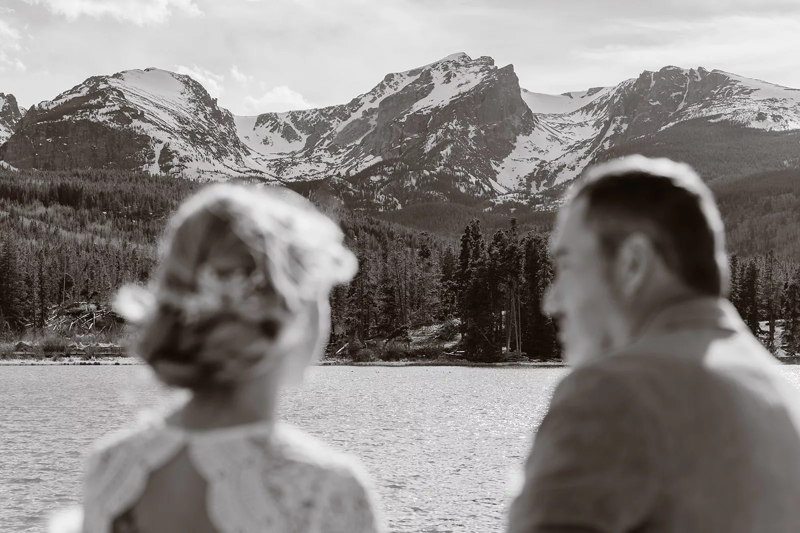 A bride and groom stare out into the mountain landscape during their elopement day, a day they planned according to their own standards.