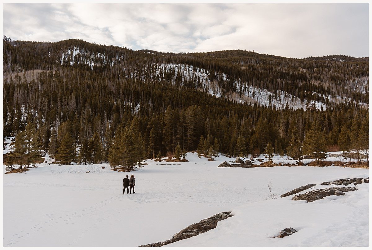 Romantic photo of the couple near snow-capped peaks during their Breckenridge proposal.