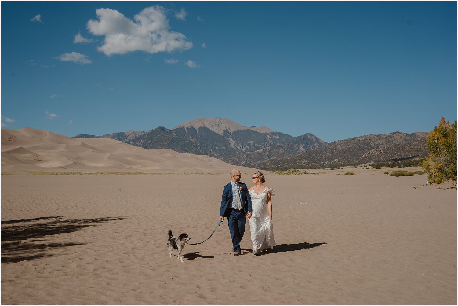 An eloping couple shares a joyful laugh while walking hand in hand through a serene alpine meadow, their love shining through in the candid moment.