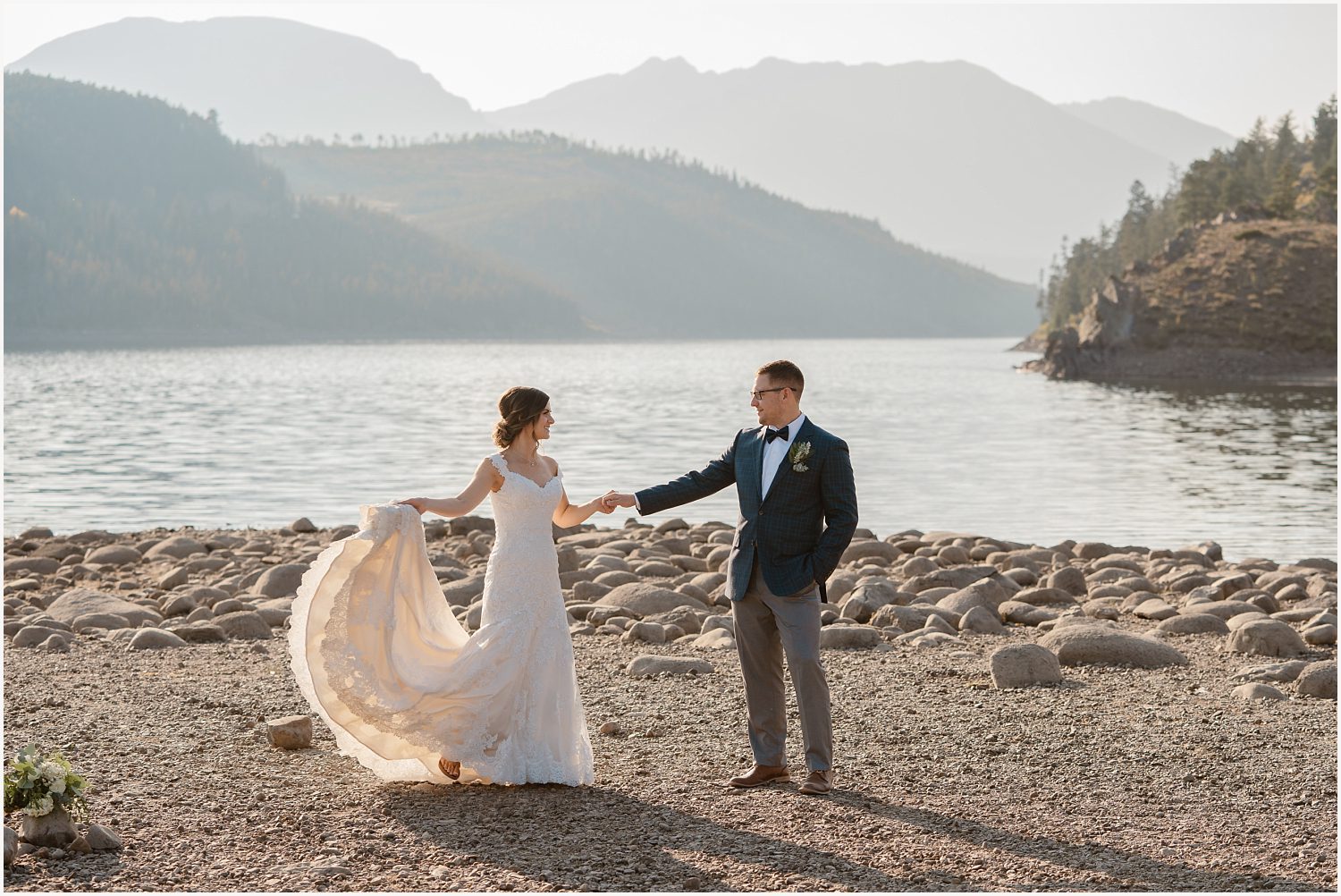 A newlywed couple embraces on a mountaintop, with golden sunlight casting a warm glow over the breathtaking Colorado landscape