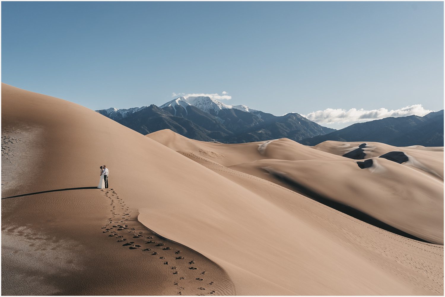 A couple stands in awe before a stunning desert vista, their love and adventurous spirits perfectly framed in the dramatic landscape.